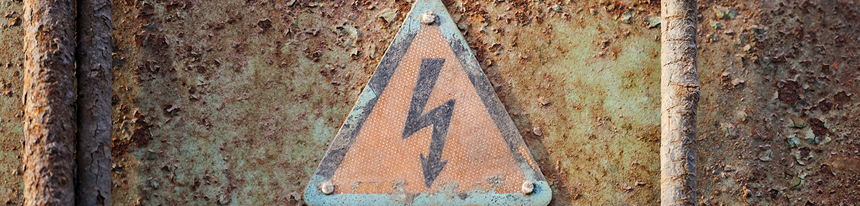 High voltage triangle sign mounted on grunge metal wall